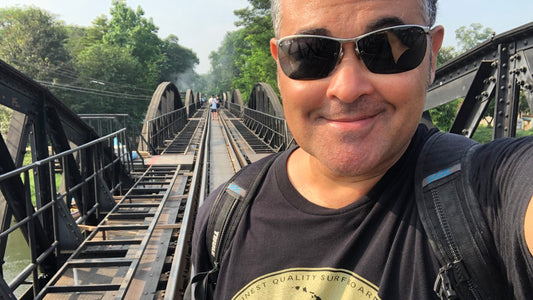 Ty Hutchinson, indie thriller author, standing on the bridge over the River Kwai during his writing travels in Southeast Asia.